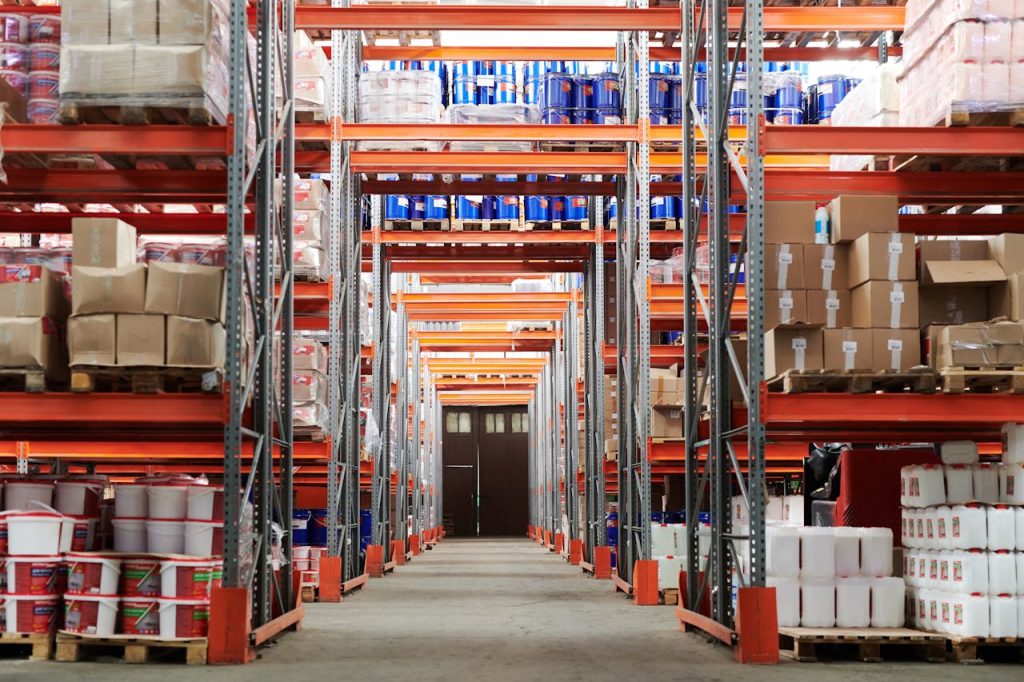 warehouse-with-concrete-floors-4483610 Wide angle view of a warehouse with stocked shelves and boxes.